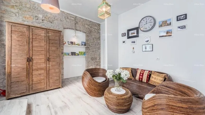 Gemütliches Wohnzimmer mit freigelegter Steinwand, hellen Holzböden und Rattanmöbeln.