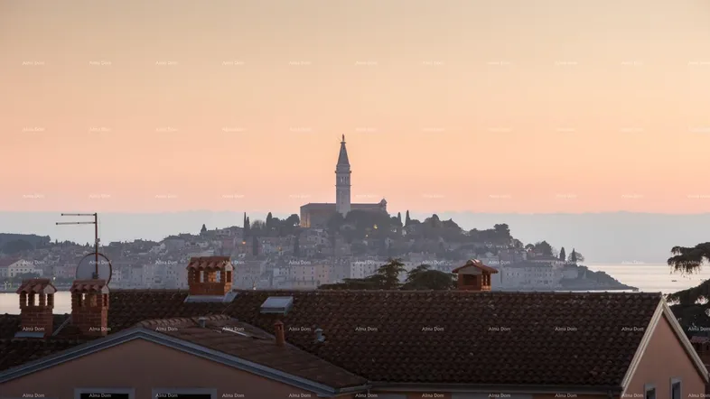 Panoramablick auf eine Küstenstadt mit Kirchturm bei Sonnenuntergang und Dächern im Vordergrund.