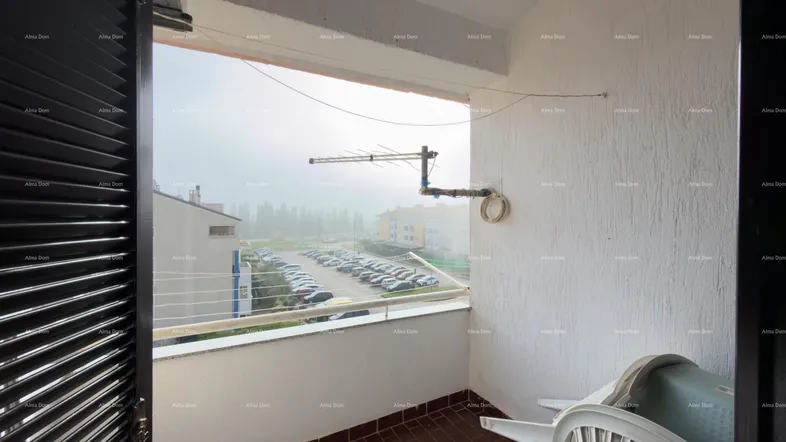 Kleiner Balkon mit braunen Fliesen, Blick auf einen Parkplatz und die Umgebung.