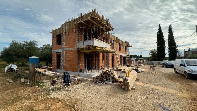 Rohbau eines Neubaus mit sichtbaren Ziegelwänden und Holzverschalung unter bewölktem Himmel.