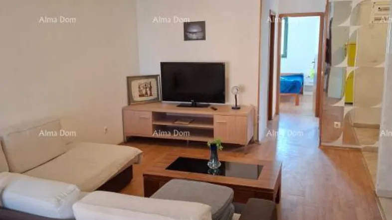Helles Wohnzimmer mit bequemen Sofas, Fernseher und Holzboden, der zu einem Flur führt.