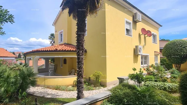 Gelbes Haus mit mediterranem Garten und Palmen unter blauem Himmel.