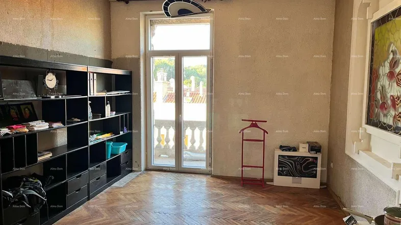 Geräumiges Wohnzimmer mit Fischgrätparkett, großem Regal und Zugang zu einem Balkon.