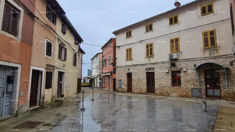 Eine nasse Gasse in einer historischen Stadt mit traditionellen Gebäuden und Fensterläden.