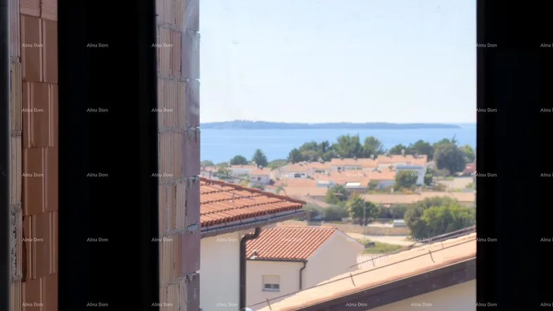 Blick aus dem Fenster auf die roten Dächer der Häuser und das blaue Meer in der Ferne.