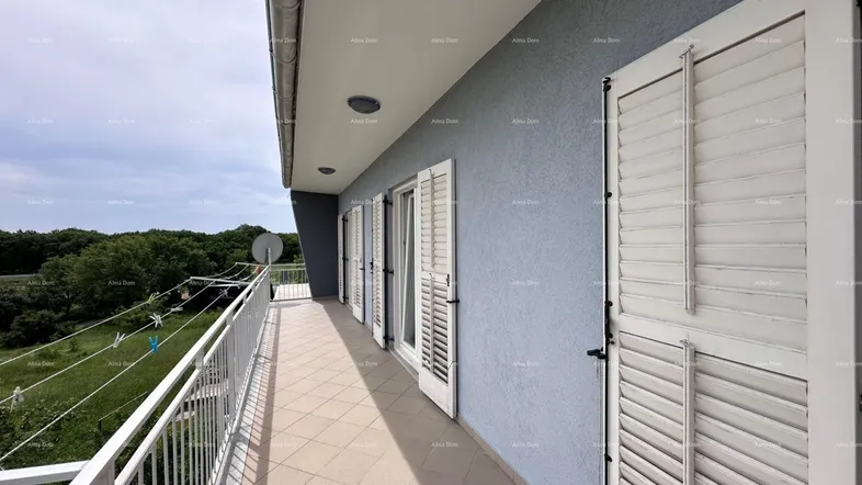Langer Balkon mit Fliesenboden, weißem Geländer und weitem Blick ins Grüne.
