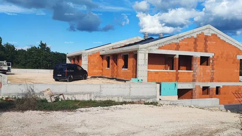 Rohbau eines Hauses mit Ziegelwänden und Betonstruktur unter blauem Himmel.