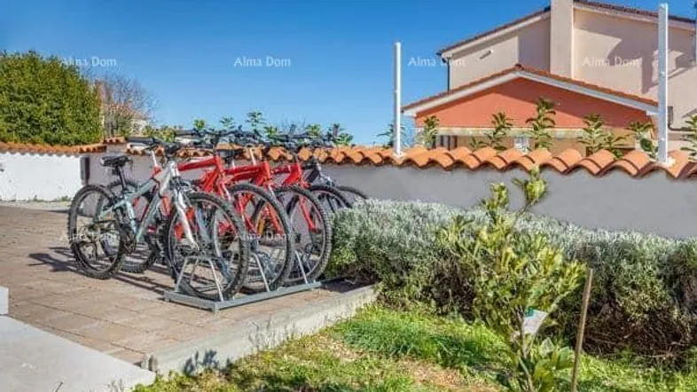 Fahrradständer mit mehreren Fahrrädern vor einem Wohngebäude unter blauem Himmel.