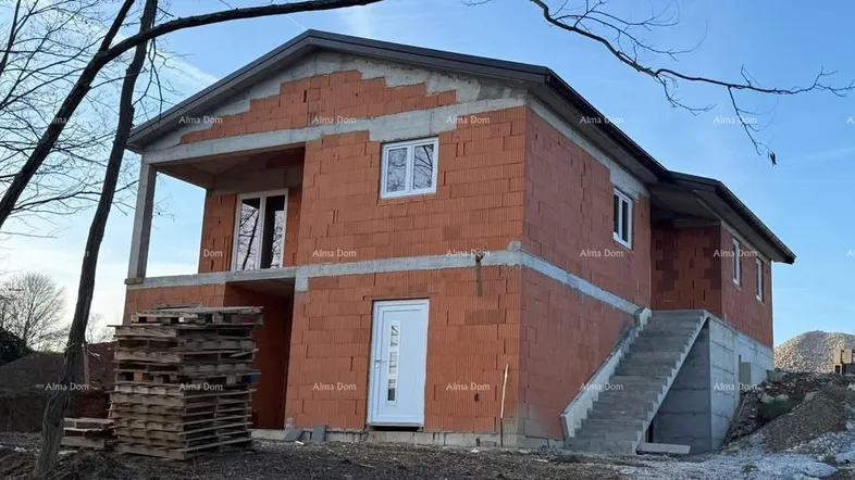 Neubau im Rohbauzustand mit Ziegelwänden und sichtbarer Betonkonstruktion, umgeben von natürlicher Landschaft.