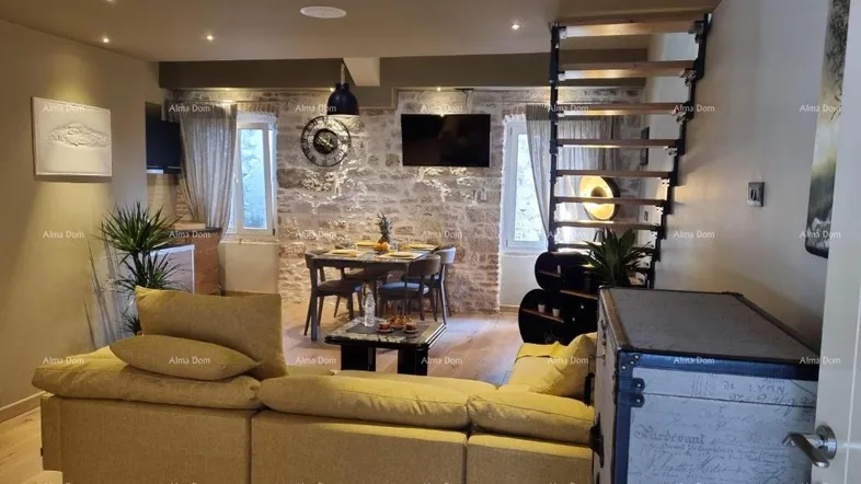 Offener Wohn- und Essbereich mit gelbem Sofa, rustikaler Steinwand und moderner Treppe zum Loft.
