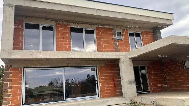 Unfertiges modernes Haus mit großen Fenstern und Rohbauwänden, bereit für den Innenausbau.