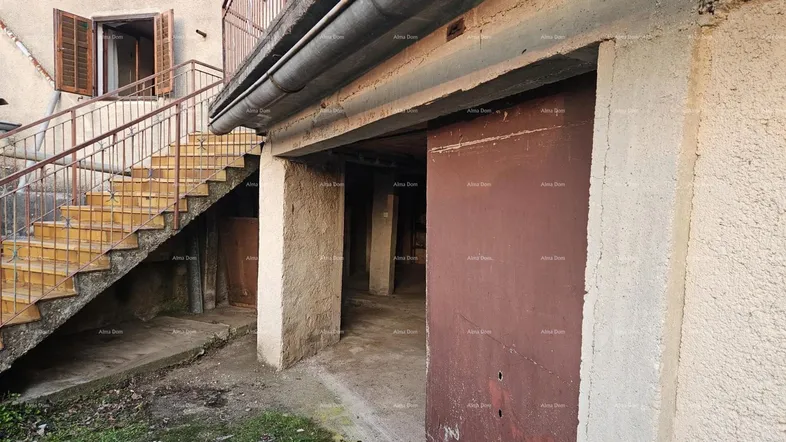 Alter Garagenbereich mit offener Einfahrt und einer Außentreppe zum Obergeschoss des Gebäudes.