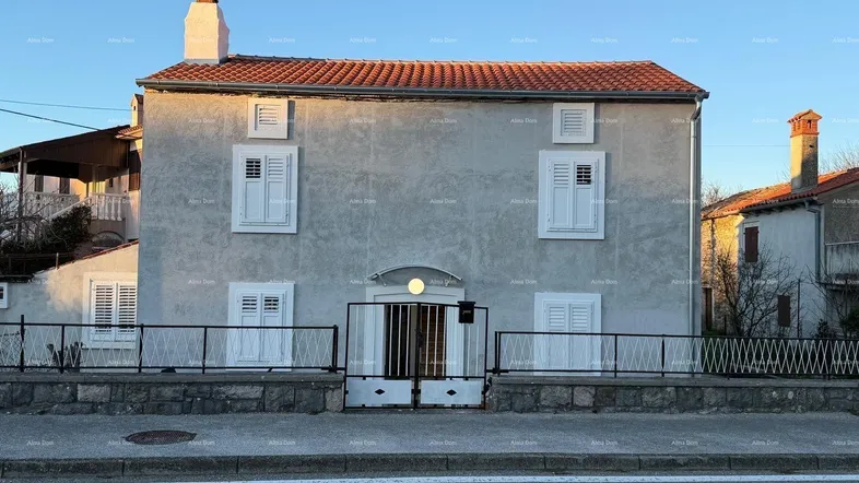 Traditionelles Haus mit verputzter Fassade, roten Dachziegeln und weißen Fensterläden.