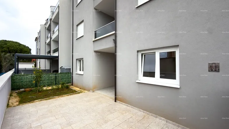 Moderne Wohnanlage mit gepflasterter Terrasse und Blick auf den Gartenbereich.
