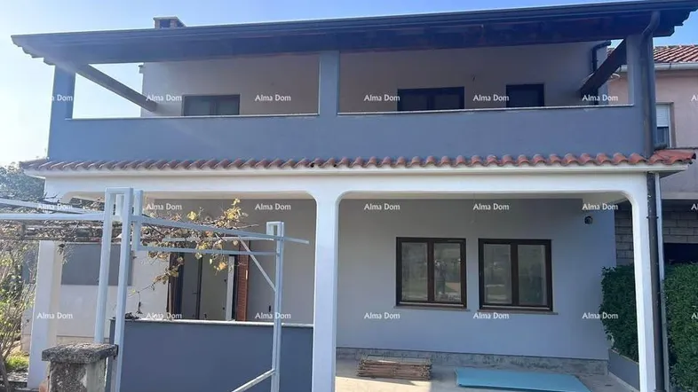 Modernes zweistöckiges Haus mit Balkonen und überdachter Terrasse im Erdgeschoss.