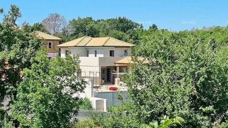 Haus mit Ziegeldach, umgeben von üppiger grüner Vegetation unter blauem Himmel.