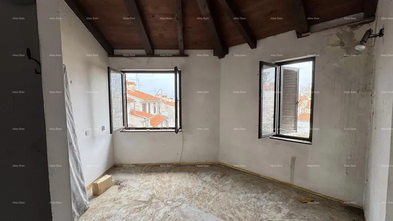 Unfertiger Innenraum mit sichtbaren Holzbalken an der Decke und Blick auf die umliegenden Gebäude.
