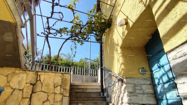 Außentreppe führt zum Eingang des Hauses mit gelber Fassade und blauer Tür.