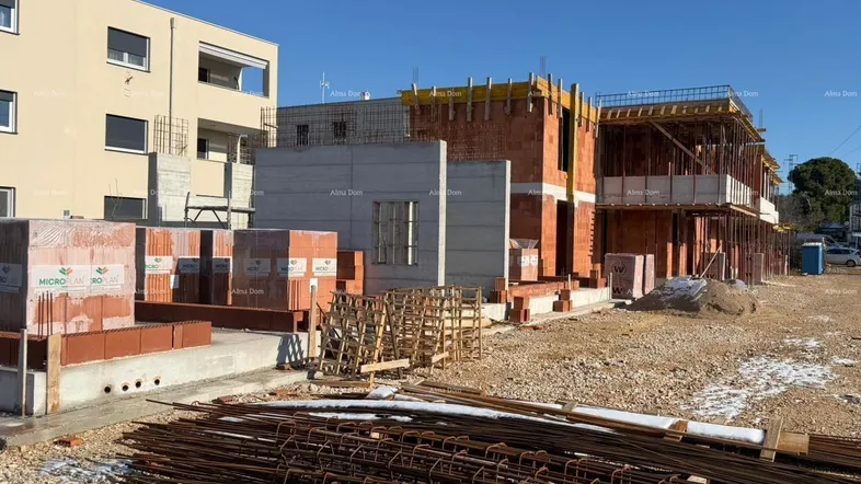 Baustelle mit im Bau befindlichen Gebäuden und Baumaterialien unter blauem Himmel.