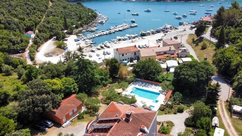 Luftaufnahme des Anwesens mit Pool, umgeben von üppiger Vegetation und Blick auf die Bucht mit Yachthafen.