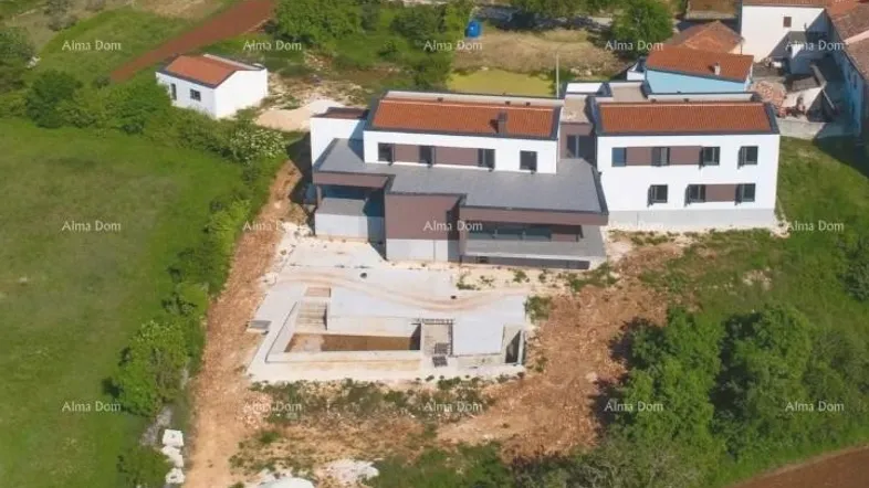 Luftaufnahme eines modernen Hauses im Bau mit Rohbau des Pools und umliegender Landschaft.