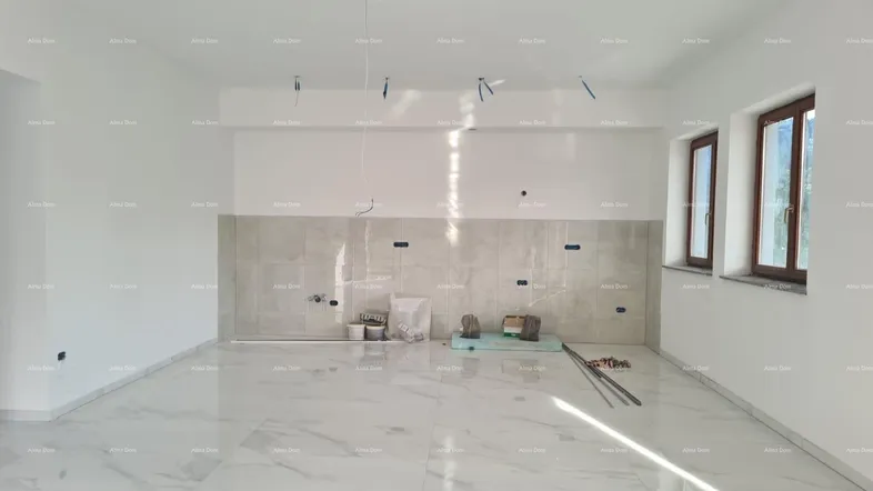 Helle, unmöblierte Küche im Rohbau mit Fliesenboden und vorbereiteten Anschlüssen für die Einrichtung.