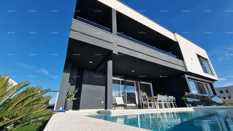 Moderne Villa mit Infinity-Pool und Terrasse, umgeben von mediterraner Vegetation unter blauem Himmel.