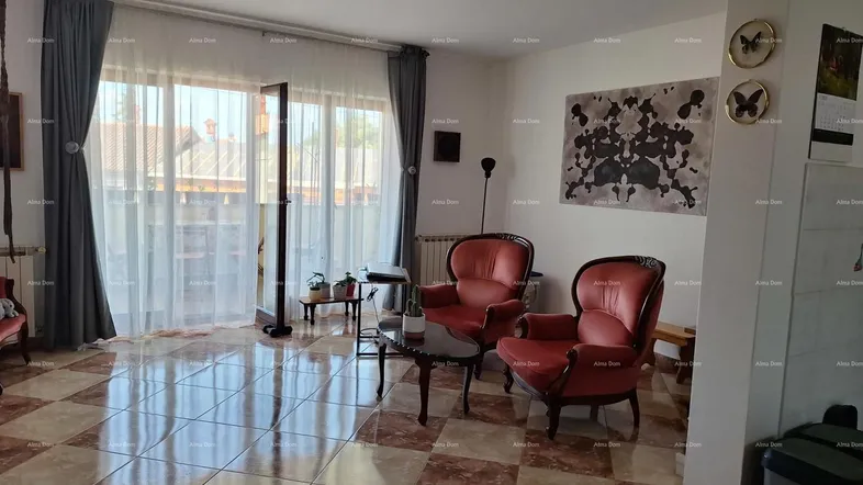 Helles Wohnzimmer mit karierten Fliesen, zwei roten Sesseln und Zugang zum Balkon.