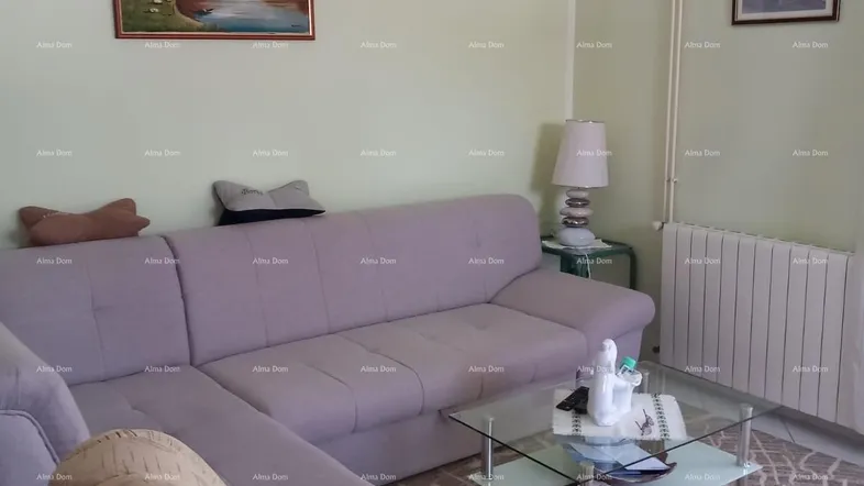 Gemütliches Wohnzimmer mit beiger Eckcouch, Couchtisch aus Glas und hellgrünen Wänden.
