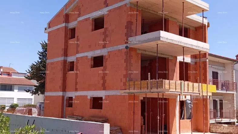 Rohbau eines Mehrfamilienhauses mit Ziegelwänden und Betondecken unter blauem Himmel.