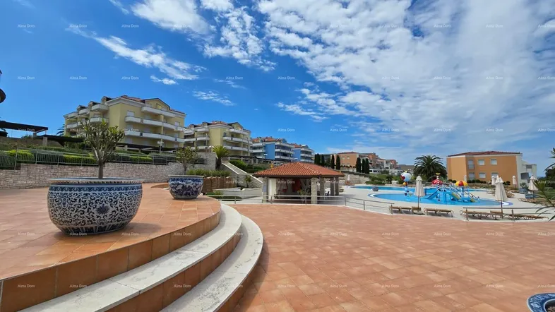 Großer Außenbereich mit Pool, Sonnenterrasse und Wohngebäuden unter blauem Himmel.