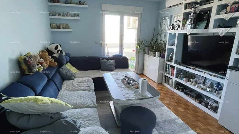 Geräumiges Wohnzimmer mit großem Ecksofa, TV-Wandregal und Zugang zum Balkon.