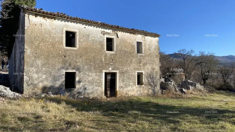 Altes, verfallenes Steinhaus mit bröckelndem Putz und leeren Fensteröffnungen in ländlicher Umgebung.