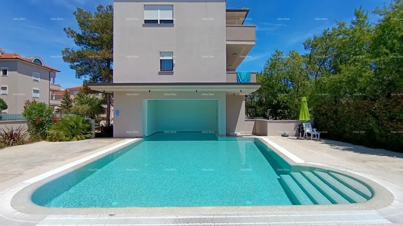 Großer Außenpool mit klarem Wasser vor einem modernen Gebäude unter blauem Himmel.