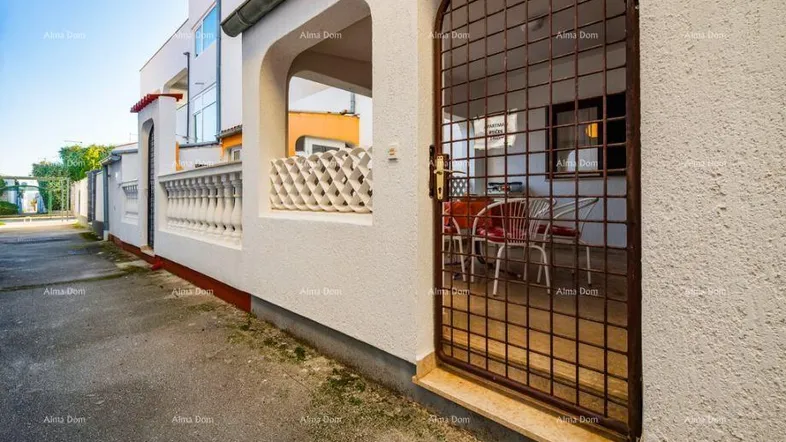 Eingangsbereich mit schmiedeeisernem Tor und Blick auf eine möblierte Terrasse.