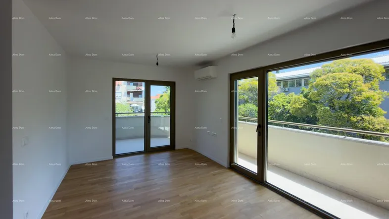 Helles Wohnzimmer mit Holzboden und Zugang zu zwei Balkonen, bietet viel natürliches Licht und eine grüne Aussicht.