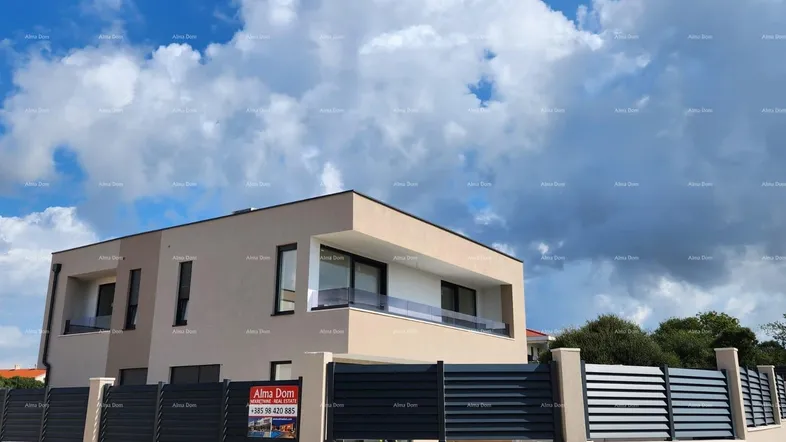 Moderne Villa mit beiger Fassade und dunklen Fensterrahmen unter bewölktem Himmel.