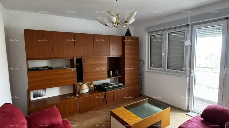 Gemütliches Wohnzimmer mit rotem Sofa, Holzmöbeln und Zugang zum Balkon.