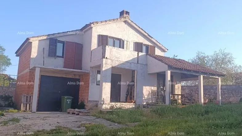 Freistehendes Haus mit Garage und überdachtem Eingangsbereich, umgeben von einer grünen Wiese.