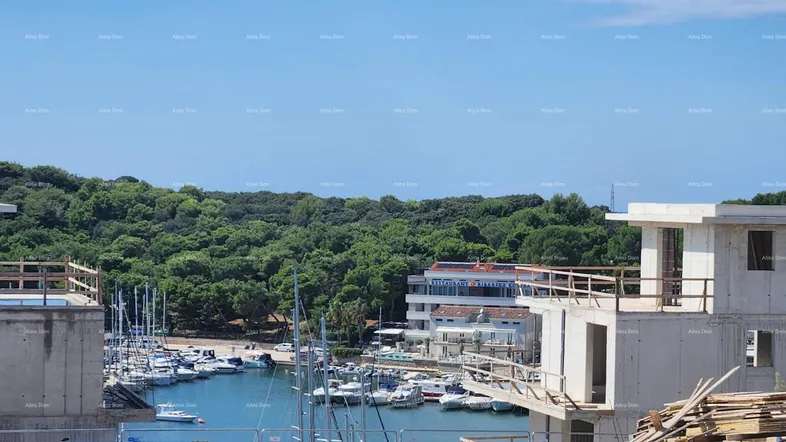 Baustelle mit Blick auf den Hafen und die umliegende grüne Landschaft unter blauem Himmel.