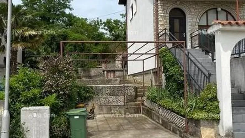 Mehrstöckiges Gebäude mit Steinfassade, Balkonen und Außentreppe.