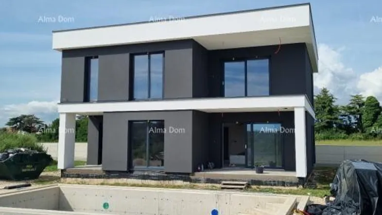 Modernes Haus im Bau mit dunkler Fassade und Rohbau eines Pools im Vordergrund.