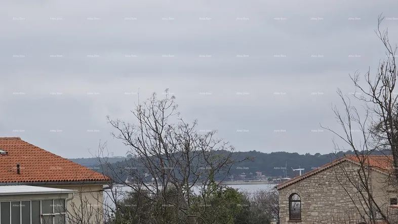 Blick auf das Meer und die umliegende Landschaft mit traditionellen Dächern unter bewölktem Himmel.