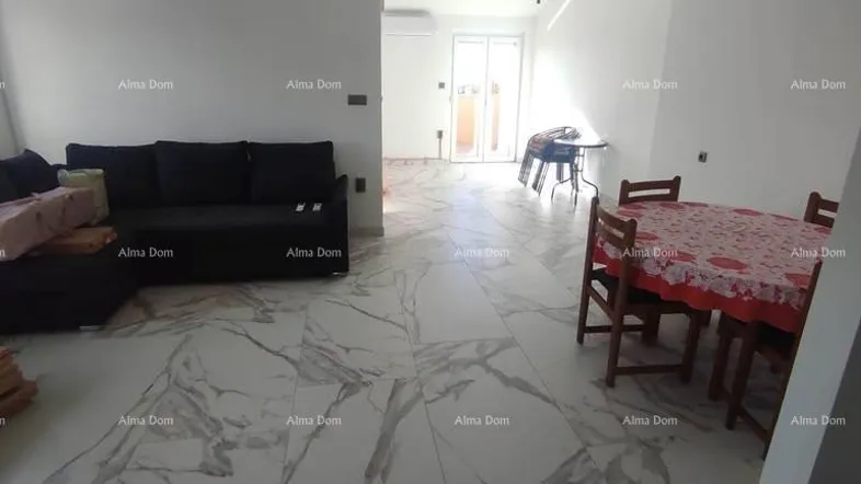 Heller Wohn- und Essbereich mit schwarzem Sofa, Esstisch und Zugang zu einem Außenbereich.