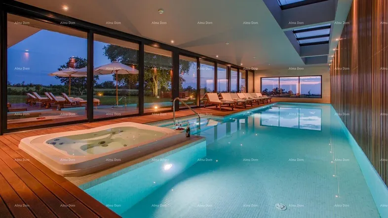 Luxuriöser Innenpool mit integriertem Whirlpool und großen Glasfronten, die den Blick auf die Landschaft freigeben.
