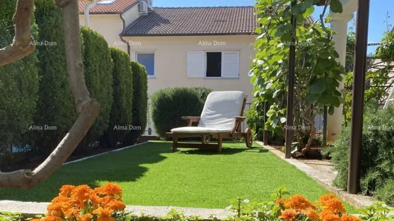 Kleiner, gepflegter Gartenbereich mit Kunstrasen, Sonnenliege und blühenden Pflanzen.