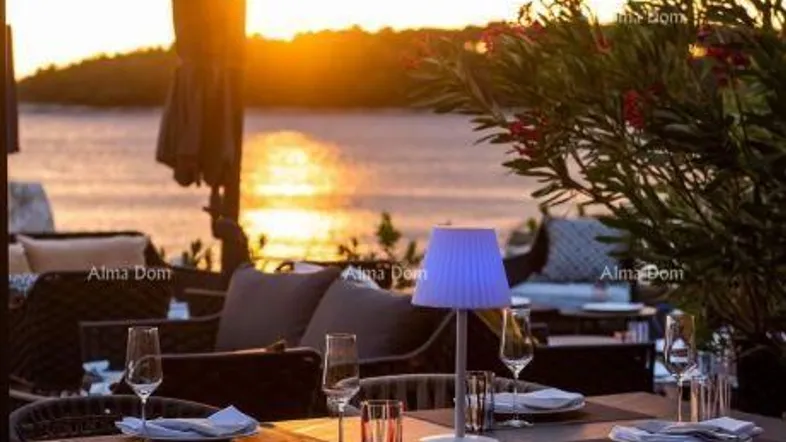 Gemütlicher Essbereich im Freien bei Sonnenuntergang mit Blick auf das Meer und eine Insel.