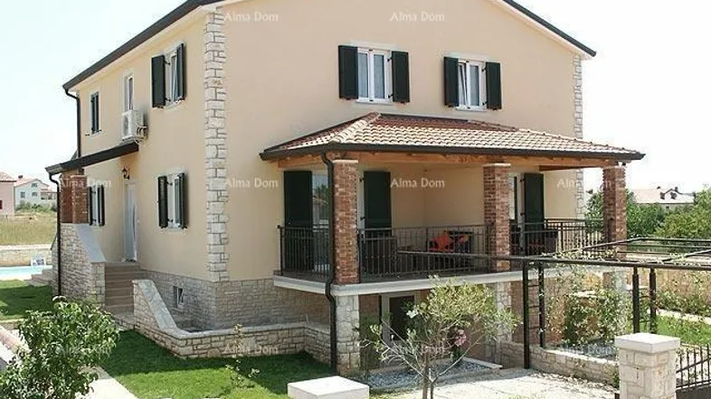 Zweistöckiges Haus mit beiger Fassade, dunklen Fensterläden und überdachtem Balkon.