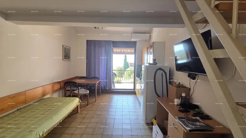 Heller Wohn- und Schlafbereich mit integrierter Küchenzeile, Esstisch und Zugang zu einem Balkon.