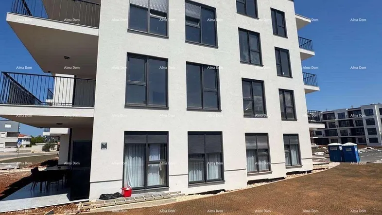 Modernes Mehrfamilienhaus mit weißer Fassade und Balkonen, umgeben von einer Baustelle.